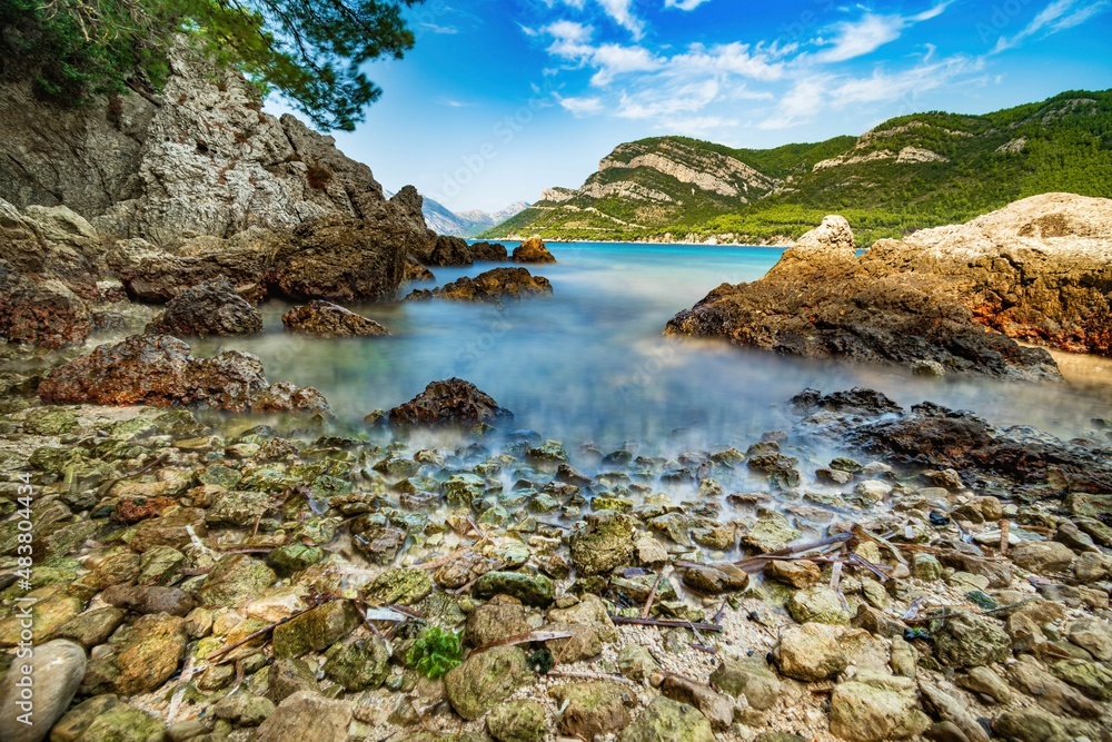 Fototapeta premium Wybrzeże i morze Chorwacji z kamienną plażą i niebieskim niebem z białymi chmurami