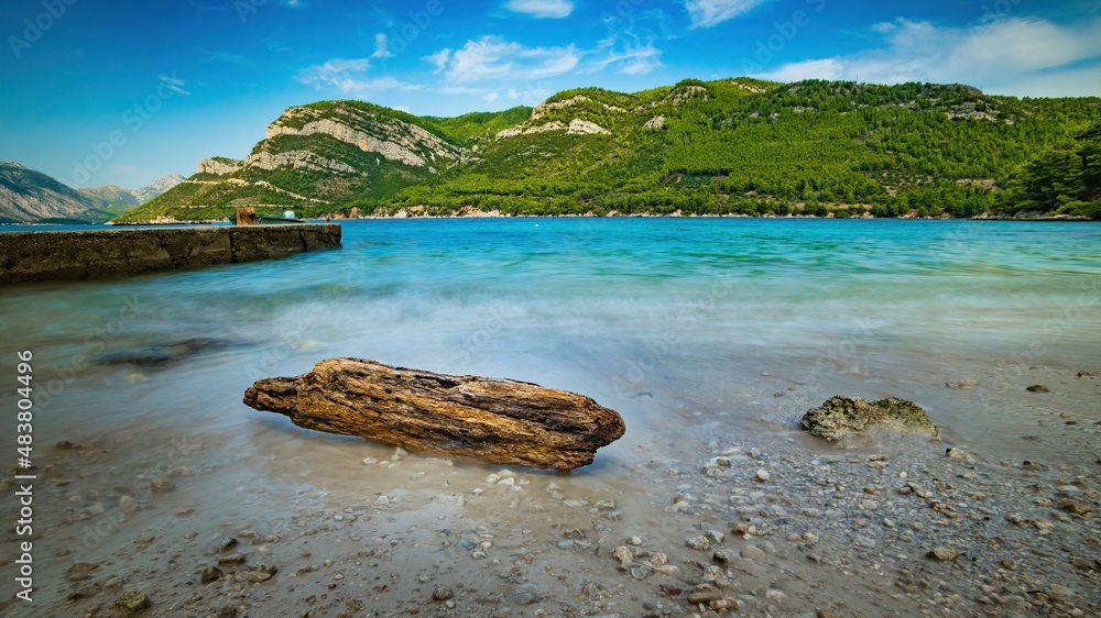 Wybrzeże i morze Chorwacji z kamienną plażą i niebieskim niebem z białymi chmurami - obrazy, fototapety, plakaty 