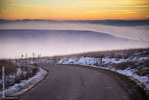 moody winter landscape with fog at sunset