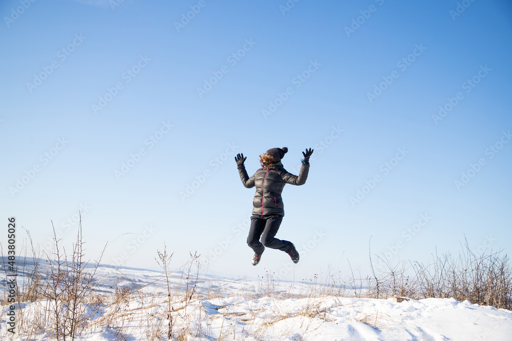 happy woman jumping outdoors in winter mindfulness