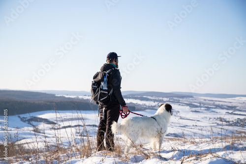 man and his happy white dog enjoying winter snow outdoors on sunny day