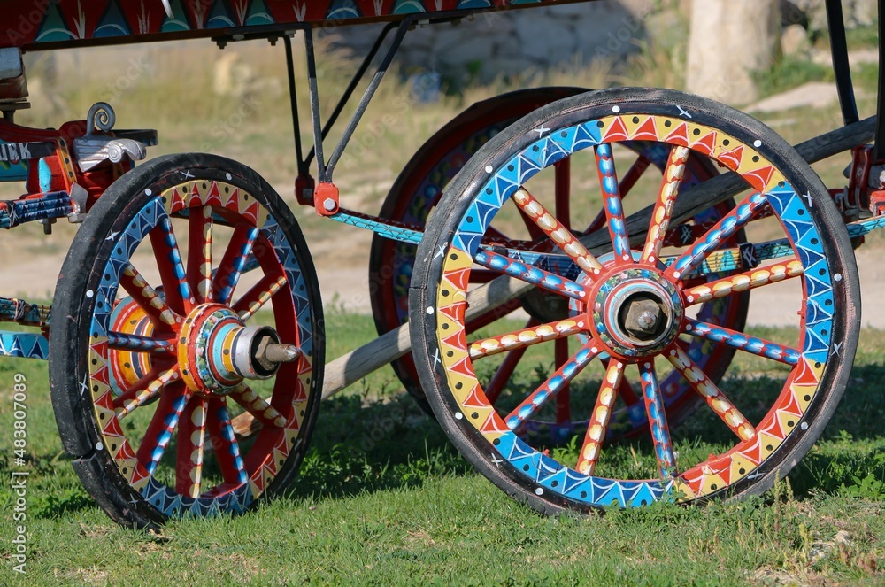 Colorful tumbrel and wheels in village.
