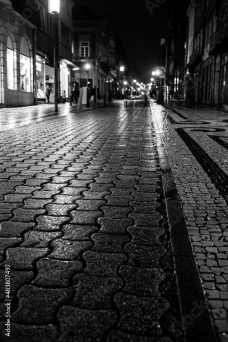 Wet after rain pavement at night in Porto, Portugal. Black and white photo.