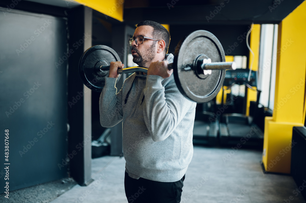 Middle aged man lifting barbell in the gym Middle aged man lifting barbell in the gym