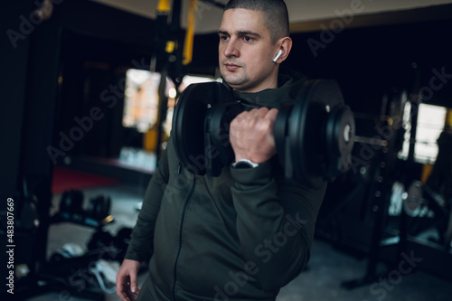Man training in the gym and lifting dumbbells