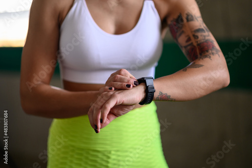 Woman in sportswear checks fitness and health tracking on her smartwatch after training