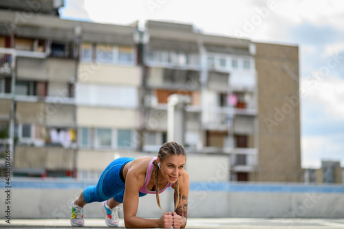 Attractive young woman in a plank position while training outside