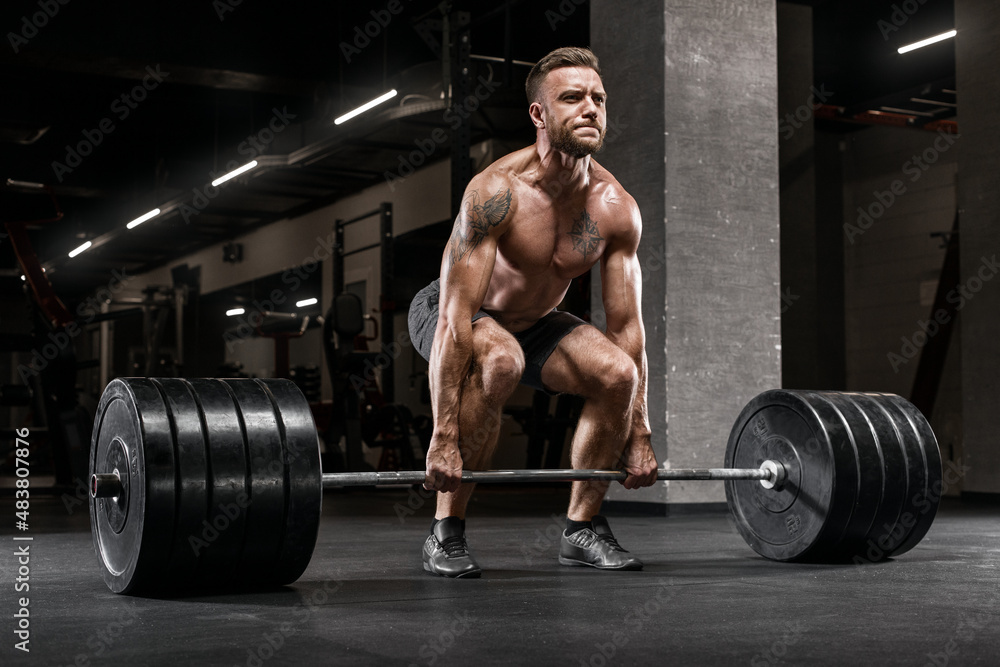 Muscular man working out in gym doing deadlift exercise, strong male naked torso abs Muscular man working out in gym doing deadlift exercise, strong male naked torso abs