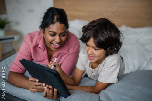 Indian mother using tablet with her little son and having fun at home.