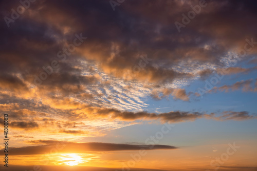 A cloudy sunset sky with yellow and orange colors as texture or background © moofushi