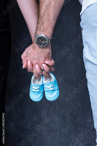 Mom and Dad are holding baby boy's shoes