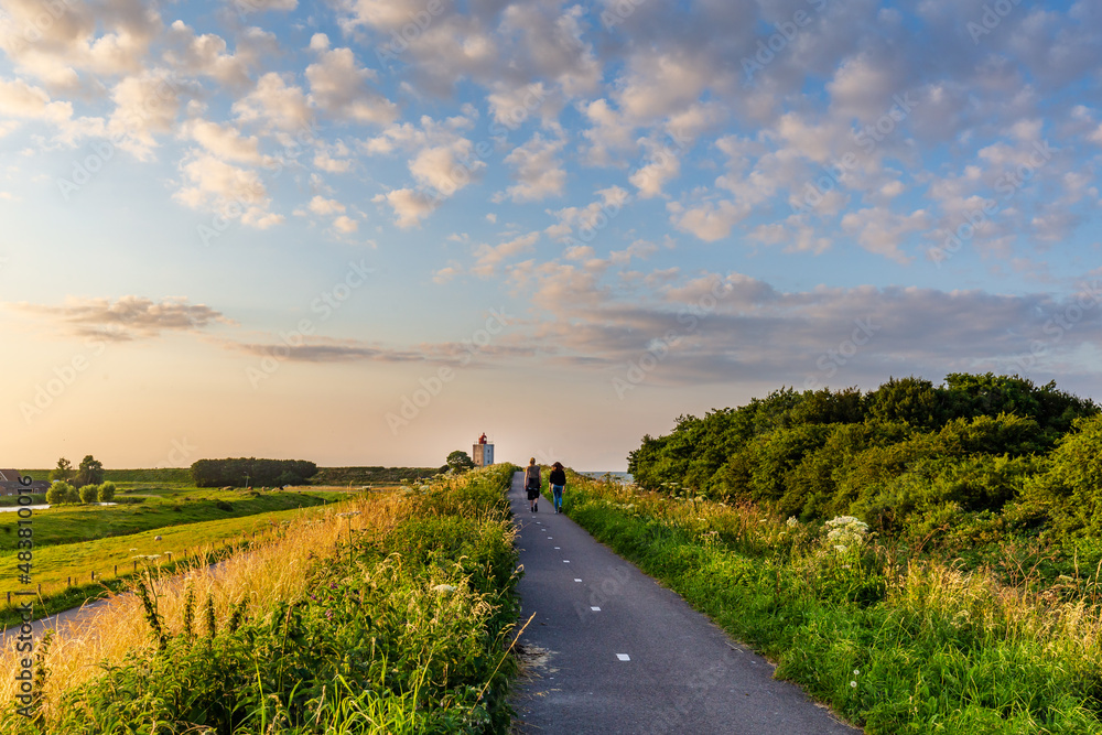 Hikers walking towards lighthouse De Ven near Edam during sunset in North-Holland in The Netherlands