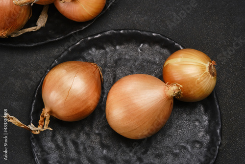 Head of onions on a black plate. Shallow depth of field