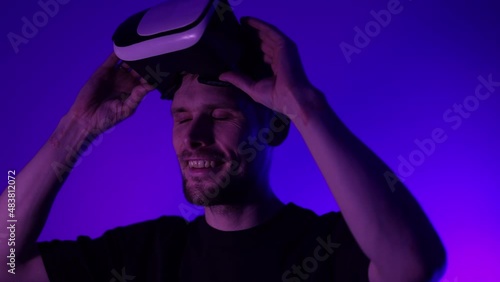 Man in metaverse using VR virtual reality glasses. Futuristic universe games and future in digital technology. Entreatment and NFT in neon colorful space. Happy male. Slow motion video in 3d cyber.