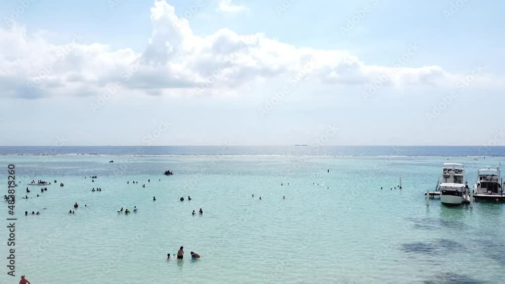 toma de drone acercandose a grupo de turistas disfrutando hermosa playa en boca chica republica dominicana.