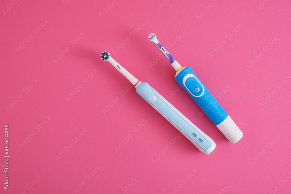 Fototapeta premium two electric blue toothbrushes on bright pink background oral hygiene concept