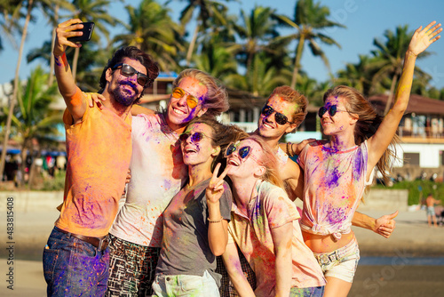 happy people in colorful holi paint play on beach on festive in Goa beach India