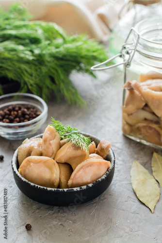 Delicious pickled mushrooms in a bowl and in a glass jar on the table. Vegetarian organic food. Close-up. Vertical view