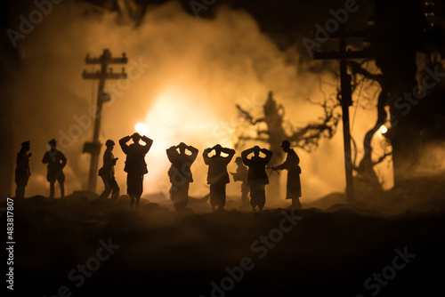 Battle scene. Military silhouettes fighting scene on war fog sky background. A German soldiers raised arms to surrender. Plastic toy soldiers with guns taking prisoner the enemy soldier. Artwork photo