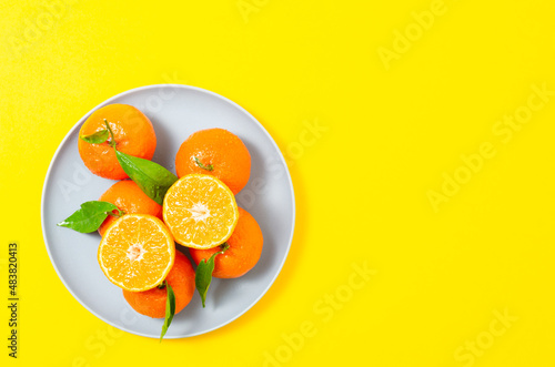 Mandarines, tangerine, clementine with leaves on yellow background. Top view 