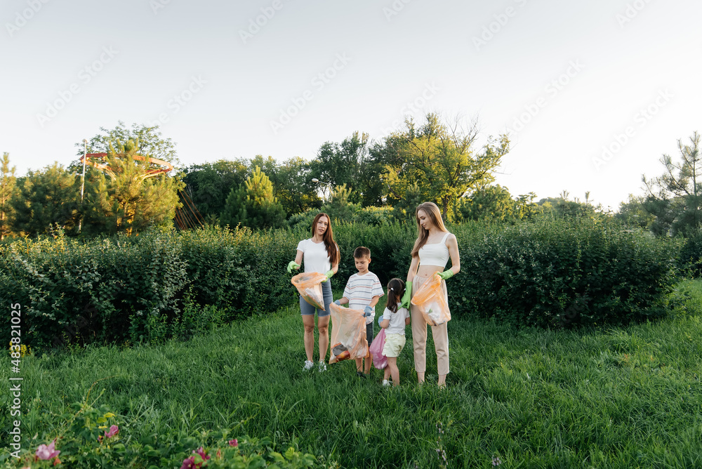 Obraz premium A group of adults and children together at sunset is engaged in garbage collection in the park. Environmental care, waste recycling. Sorting garbage.