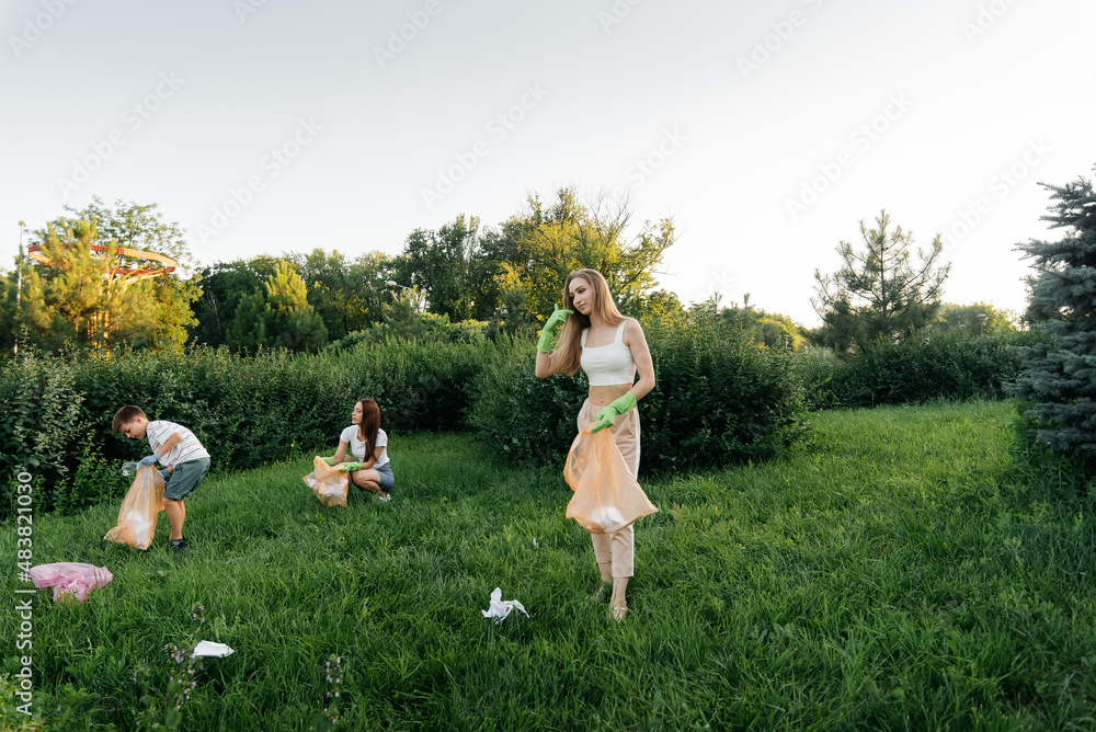 A group of adults and children together at sunset is engaged in garbage collection in the park. Environmental care, waste recycling. Sorting garbage.