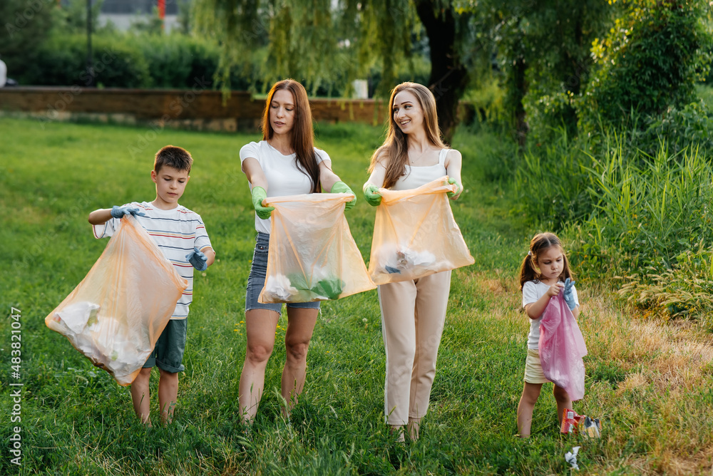 A group of adults and children together at sunset is engaged in garbage collection in the park. Environmental care, waste recycling. Sorting garbage. A group of adults and children together at sunset is engaged in garbage collection in the park. Environmental care, waste recycling. Sorting garbage.