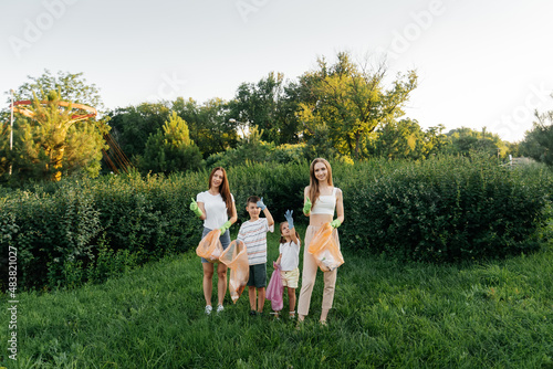 A group of adults and children together at sunset is engaged in garbage collection in the park. Environmental care, waste recycling. Sorting garbage. © Andrii