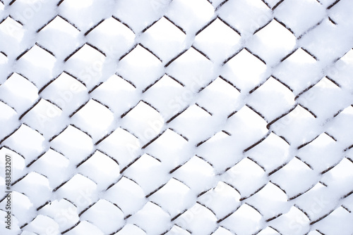 Winter background. The iron mesh netting is covered with snow