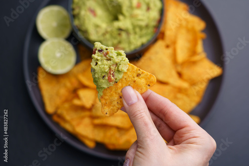 Foto Closeup of woman hand with tortilla chips or nachos with fresh tasty guacamole d