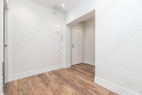 Entrance to a newly renovated residential home with chestnut wood flooring, high skirting board and plain white painted walls © Toyakisfoto.photos