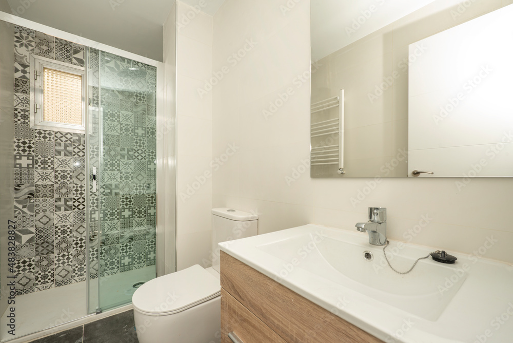 Bathroom with elongated white porcelain sink, rectangular frameless mirror and shower with glass partition and hydraulic tiles Bathroom with elongated white porcelain sink, rectangular frameless mirror and shower with glass partition and hydraulic tiles