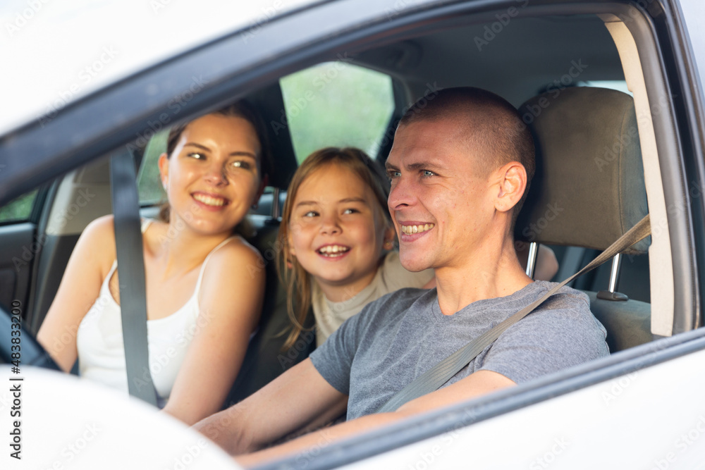 Happy friendly family with daughter travel together, they driving in car and smiling