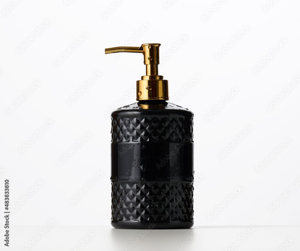 Obraz premium black plastic container with a golden dispenser on a white background. Container for liquid soap, shampoo