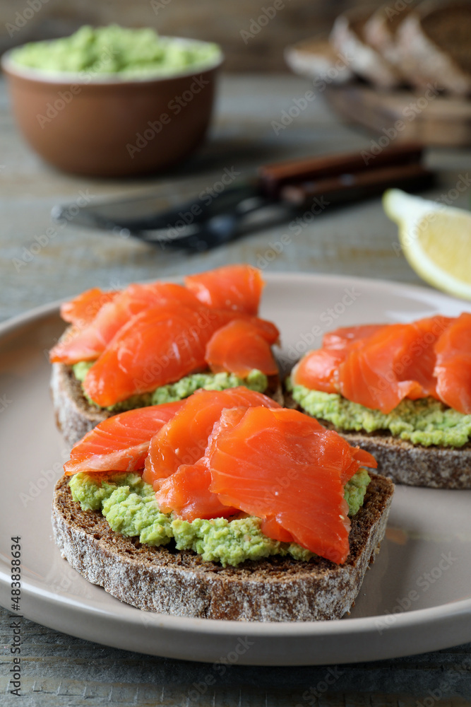 Delicious sandwiches with salmon and avocado on grey plate, closeup Delicious sandwiches with salmon and avocado on grey plate, closeup