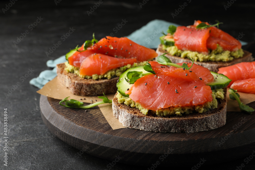 Tasty bruschettas with salmon, guacamole and microgreens on black table, closeup Tasty bruschettas with salmon, guacamole and microgreens on black table, closeup