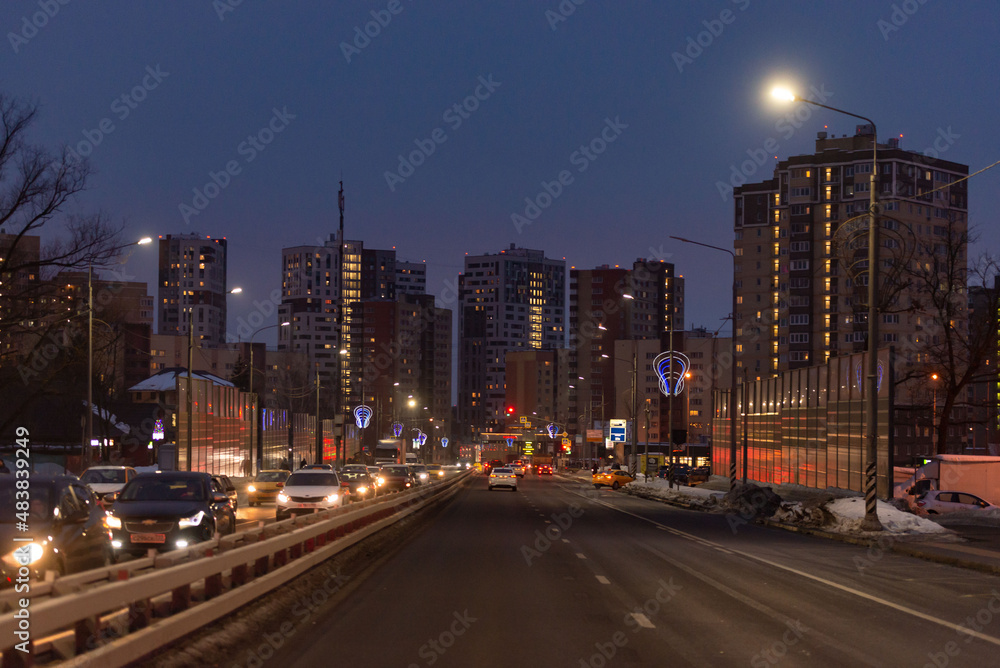 Central street in Kommunarka in winter. A lot of high-rise buildings and a lighted city highway