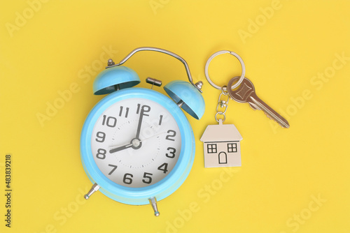 clock and house keys on a yellow background, copy space.