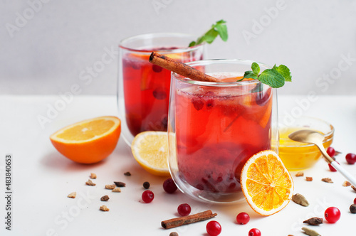 Tea with cranberry, orange, lemon, cinnamon, honey and mint on a white background. Two glasses with fruit tea and spices