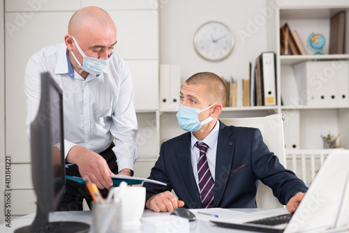 Male businessman working in an office during a pandemic makes a joint project with his business partners, discussing..the nuances