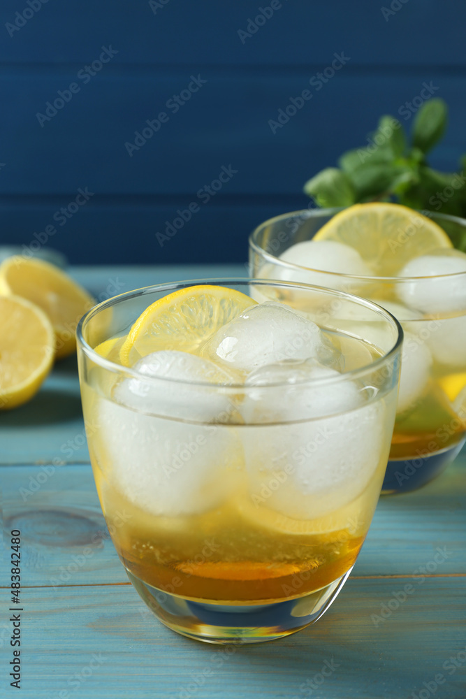 Delicious cocktails with lemon and ice balls on light blue wooden table Delicious cocktails with lemon and ice balls on light blue wooden table