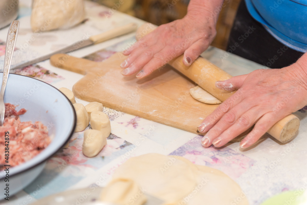 Roll out the dough. A woman rolls the dough with a rolling pin. Cooking food. Traditional dishes.
