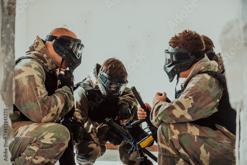 The paintball team agrees on tactics before the fight begins. Selective focus © Minet