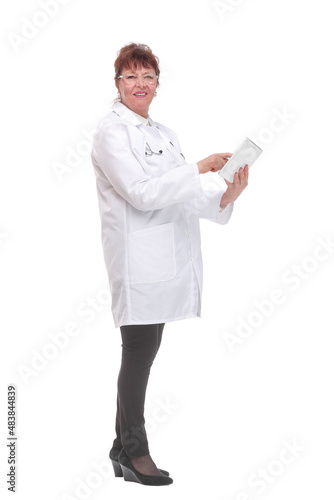 Side view of senior woman doctor with stethoscope write on tablet looking at camera