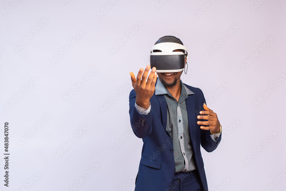 Close up portrait of handsome man playing video games in goggles or 3d glasses. african player wearing virtual reality headset for smart phone on his head, smiling, standing against white background Close up portrait of handsome man playing video games in goggles or 3d glasses. african player wearing virtual reality headset for smart phone on his head, smiling, standing against white background