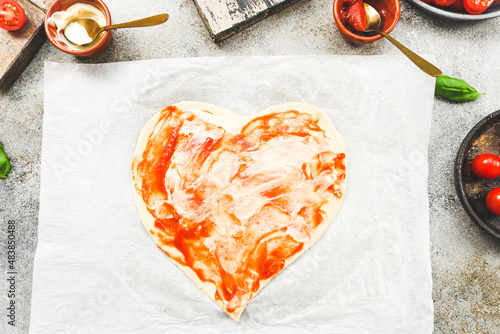 Carved from heart pizza dough on baking paper photo