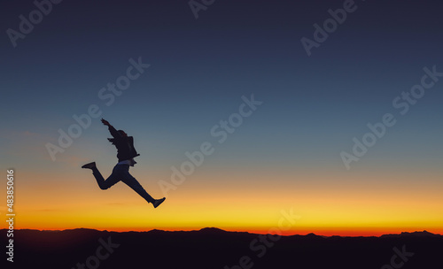 Silhouette of beautiful girl jumping on mountain park golden color sunset background.