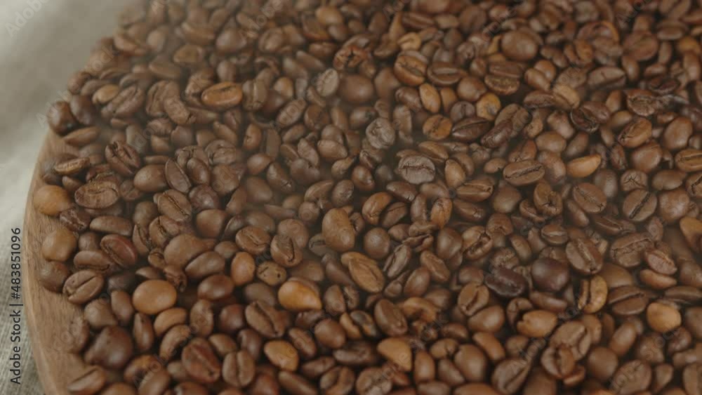 Lots of coffee beans on wooden board with dissipating steam. Roasted beans for preparation of fragrant drink. Lots of coffee beans on wooden board with dissipating steam. Roasted beans for preparation of fragrant drink.