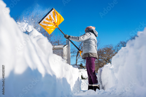 Woman shoveling snow out of driveway with movement and action.