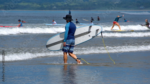 Photography Man carrying a surf board in Tamarindo, Costa Rica
